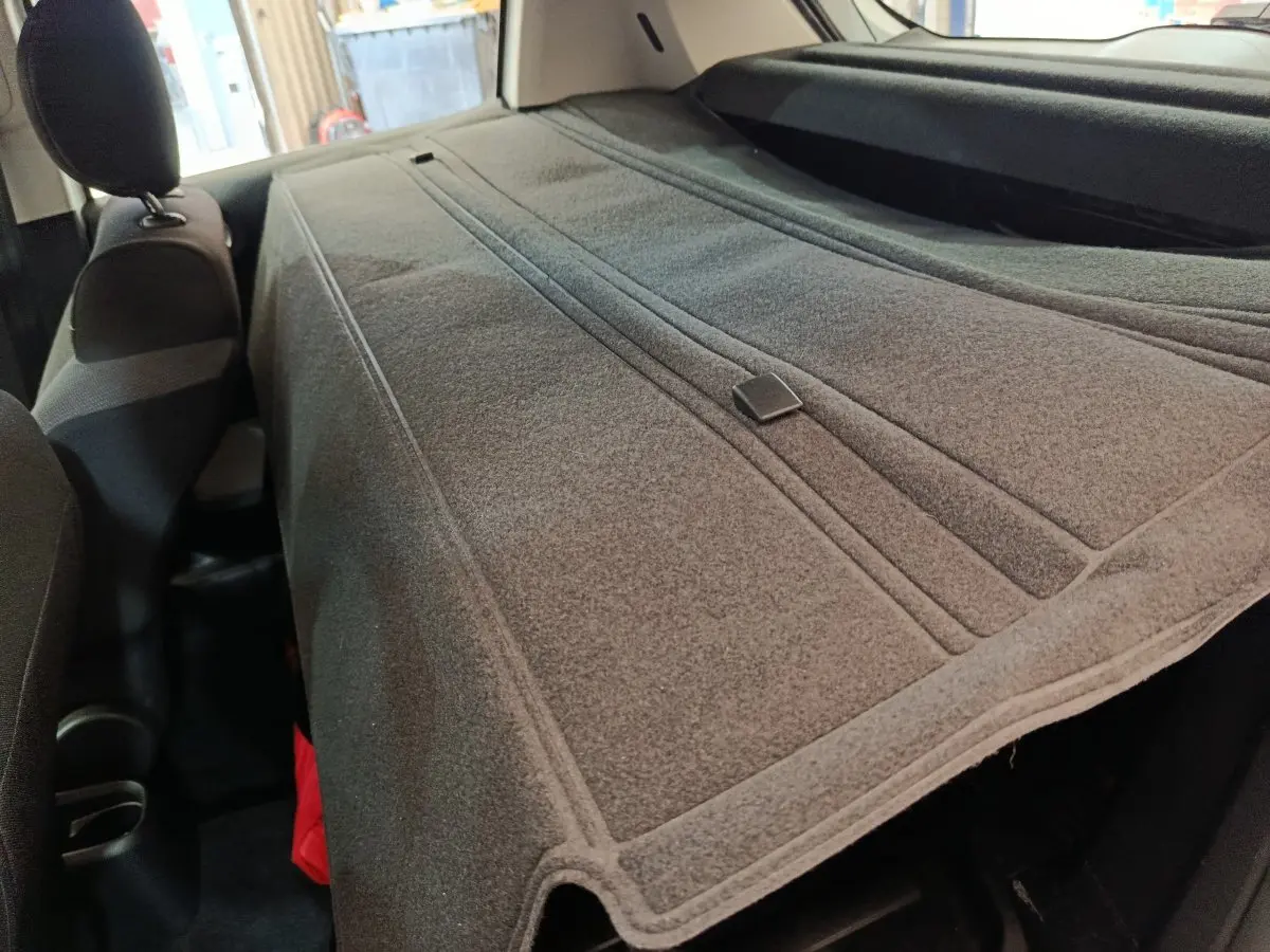 Vue intérieure du coffre de la Citroën C3 2022 avec cache-bagages gris étendu sur les sièges arrière.