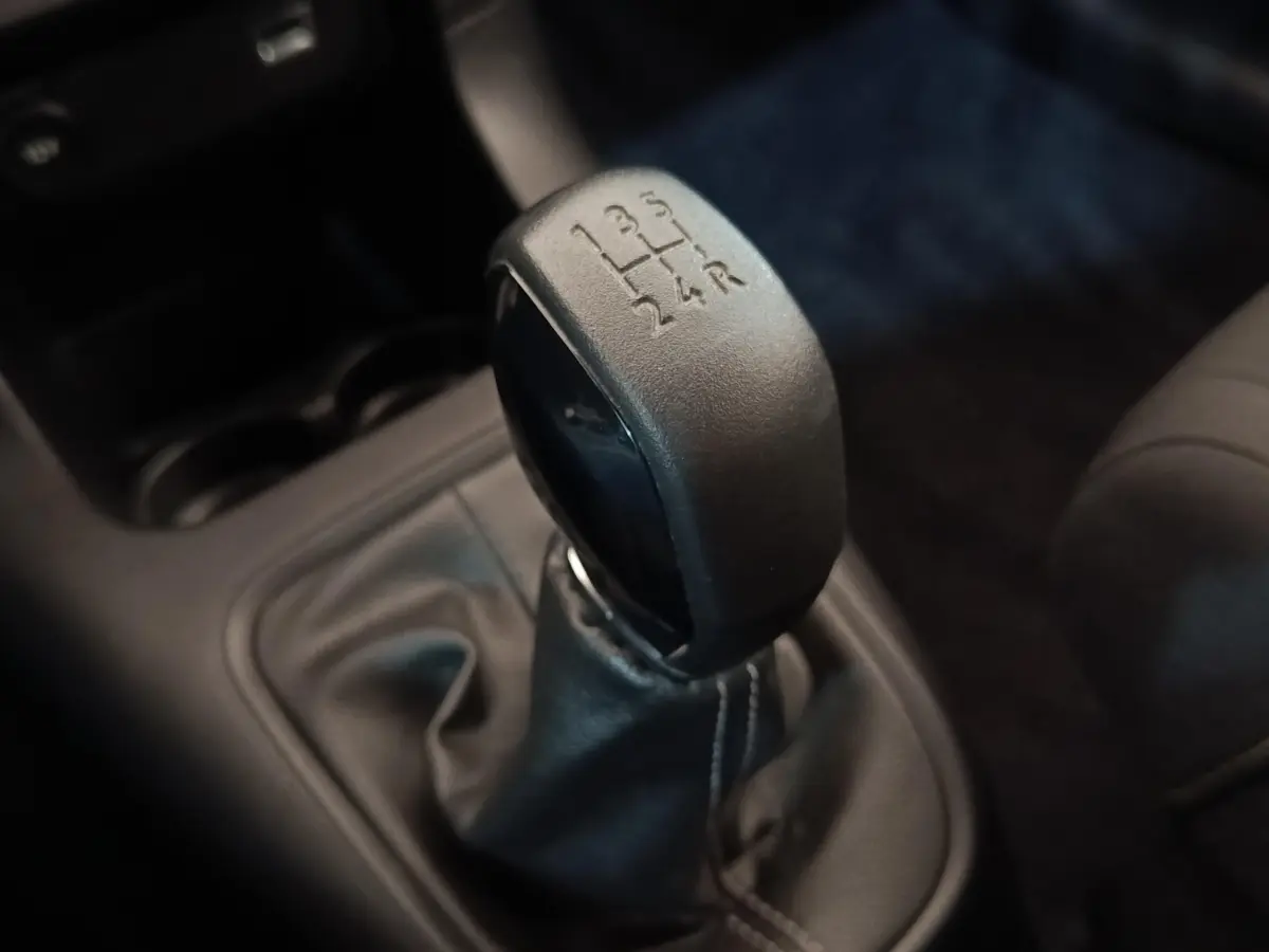 Gros plan sur le levier de vitesses manuel noir de la Citroën C3 blanche, avec indication des 5 rapports et marche arrière.