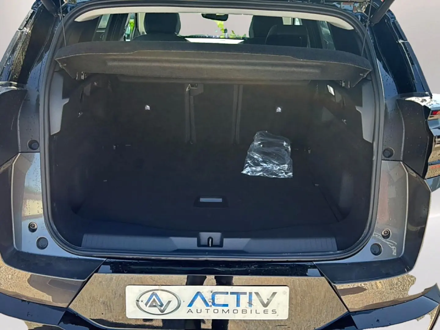 Coffre ouvert vu de l'arrière d'un Citroën C5 Aircross gris platinium avec hayon électrique et plancher de coffre mobile.