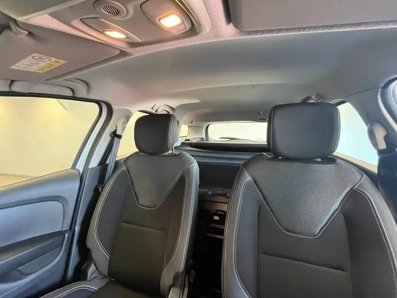 Vue intérieure avant montrant les sièges tissu noir/gris et le plafond clair d'une Renault Clio Estate blanche.