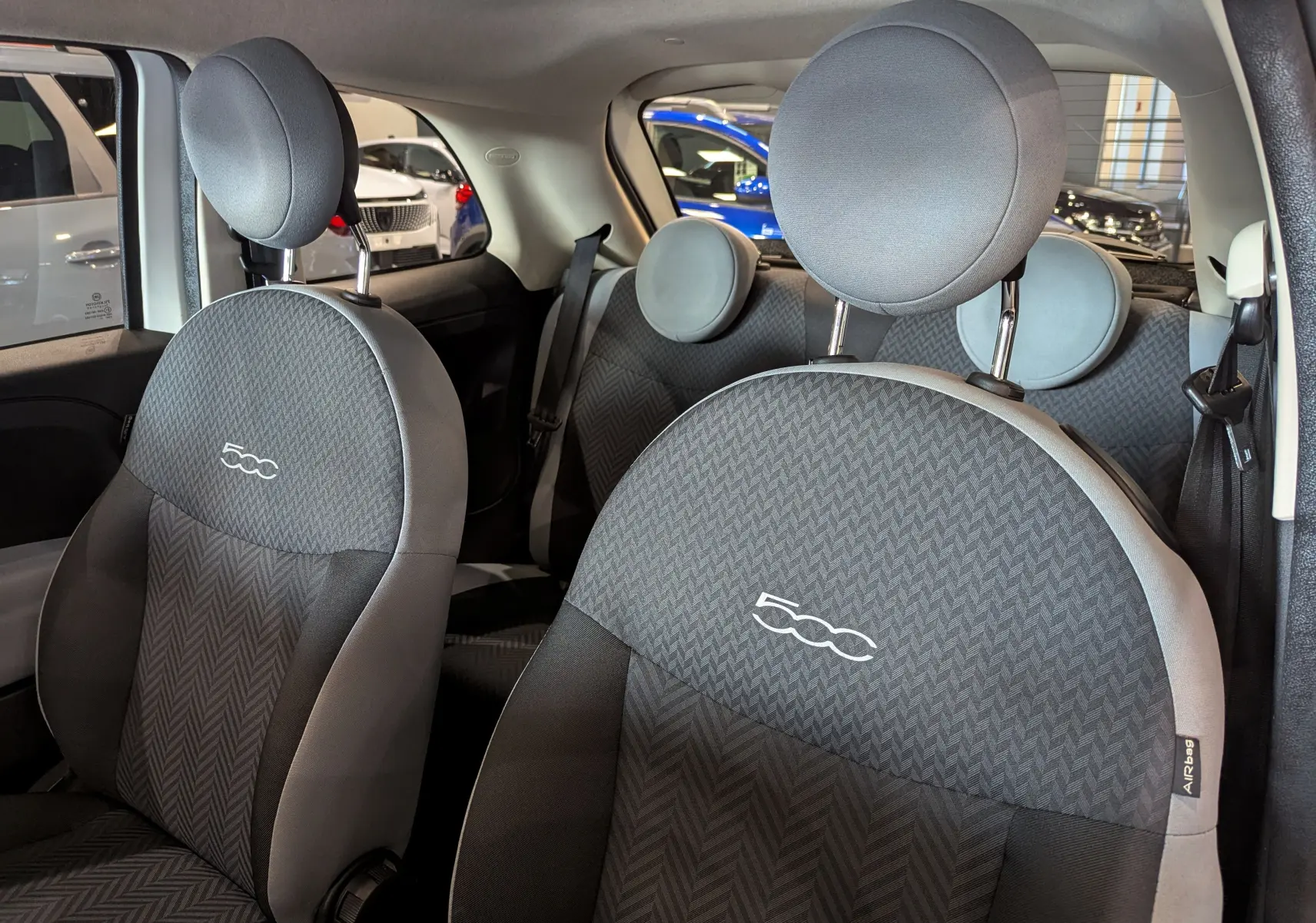 Intérieur de la Fiat 500 2018 montrant les sièges avant en tissu gris avec logo 500 brodé, vue côté droit.