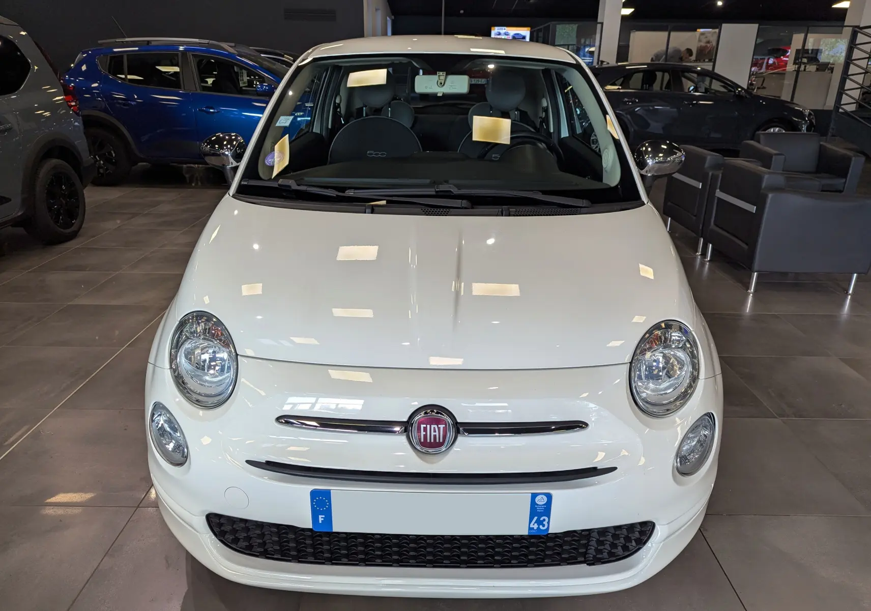 Vue de face d'une Fiat 500 blanche Bossanova 2018 exposée en showroom avec logo FIAT visible sur la calandre.