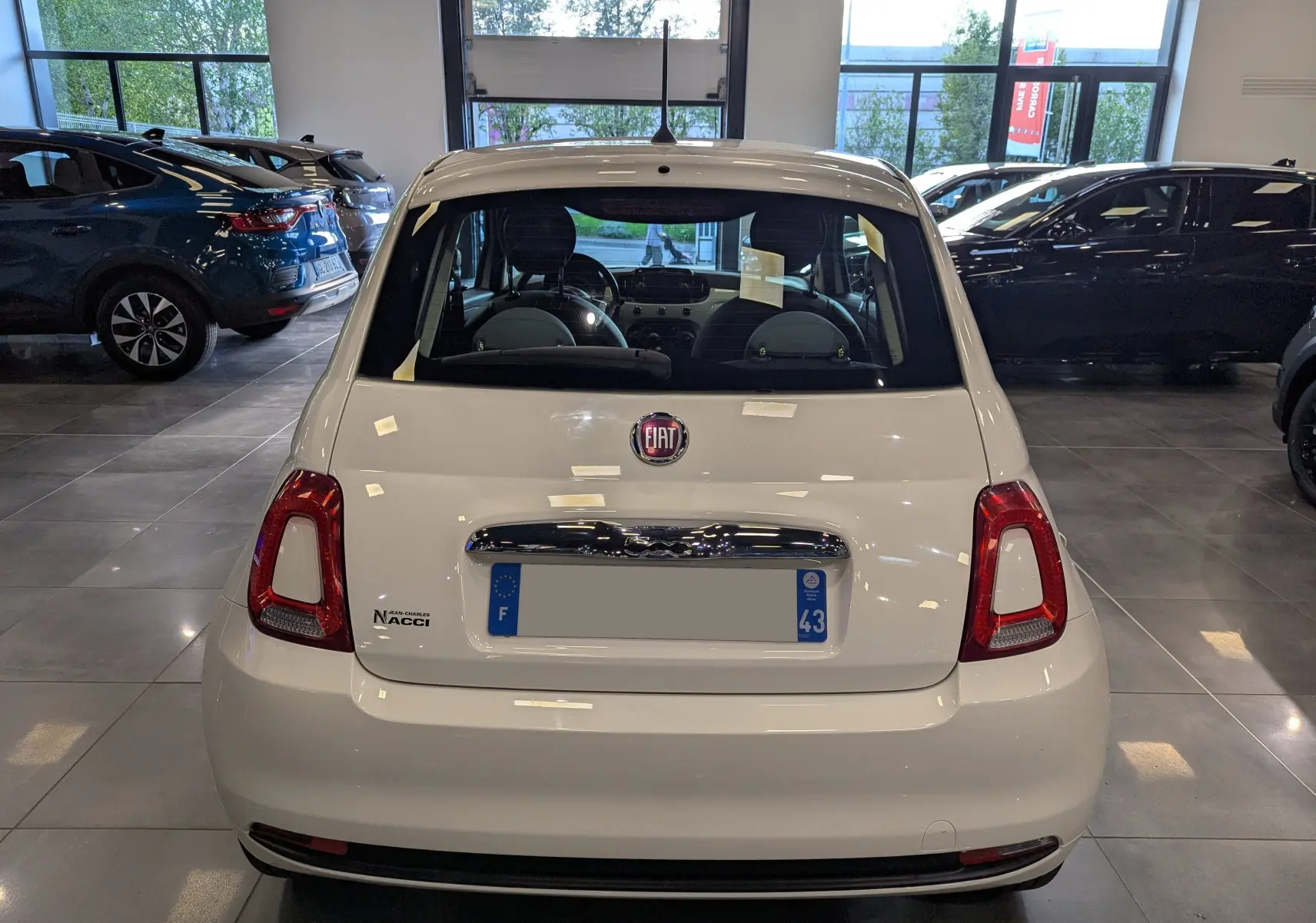 Vue arrière d'une Fiat 500 blanc Bossanova 2018 dans un showroom, avec logo et plaque d'immatriculation visibles.
