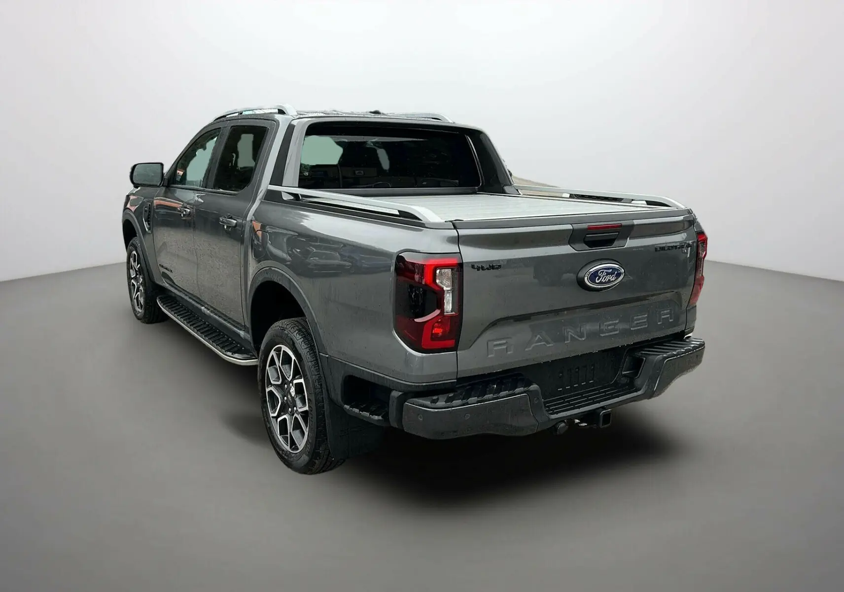 Ford Ranger 2025 gris carbone en vue 3/4 arrière droit avec benne couverte et jantes spécifiques Wildtrak Plus.