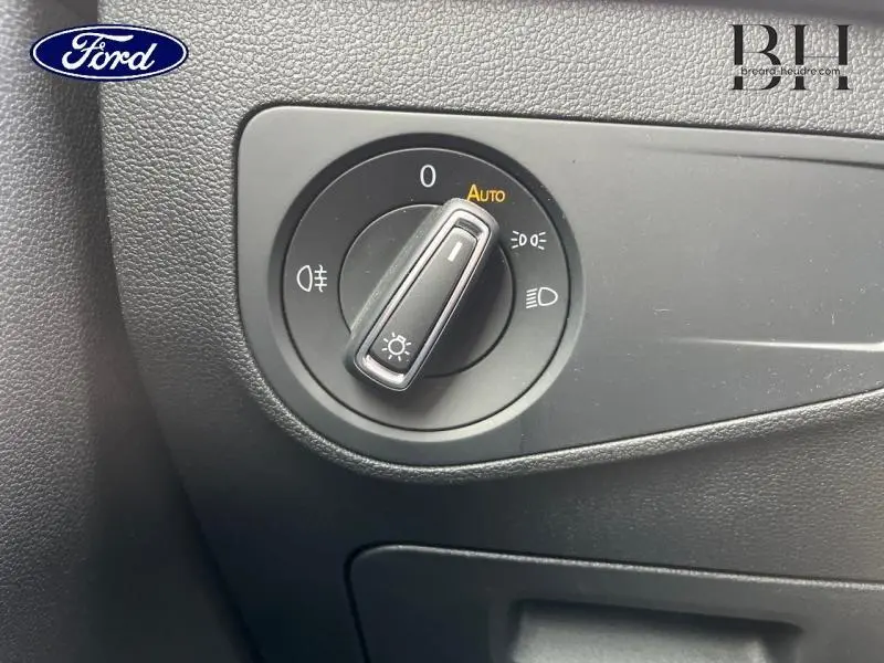 Commande des phares en gros plan sur tableau de bord noir du Volkswagen Tiguan 1.4 eHybrid 2022, mode automatique activé.