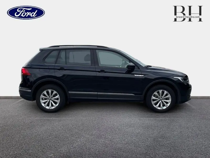 Profil droit du Volkswagen Tiguan 1.4 eHybrid 2022 en noir intense nacré avec jantes alu et barres de toit.