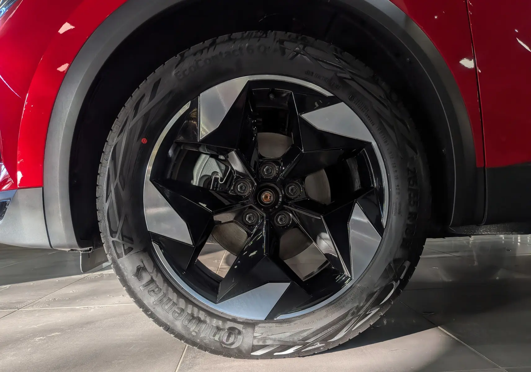 Gros plan sur la roue avant gauche du Renault Captur rouge Flamme avec jante noire et argentée au design géométrique.