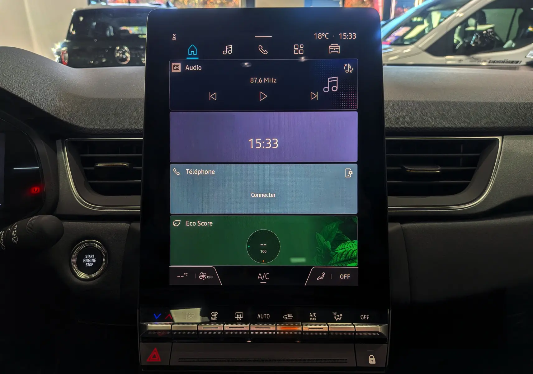 Écran tactile central du tableau de bord du Renault Captur 2025 avec commandes climatisation et bouton start/stop visible.