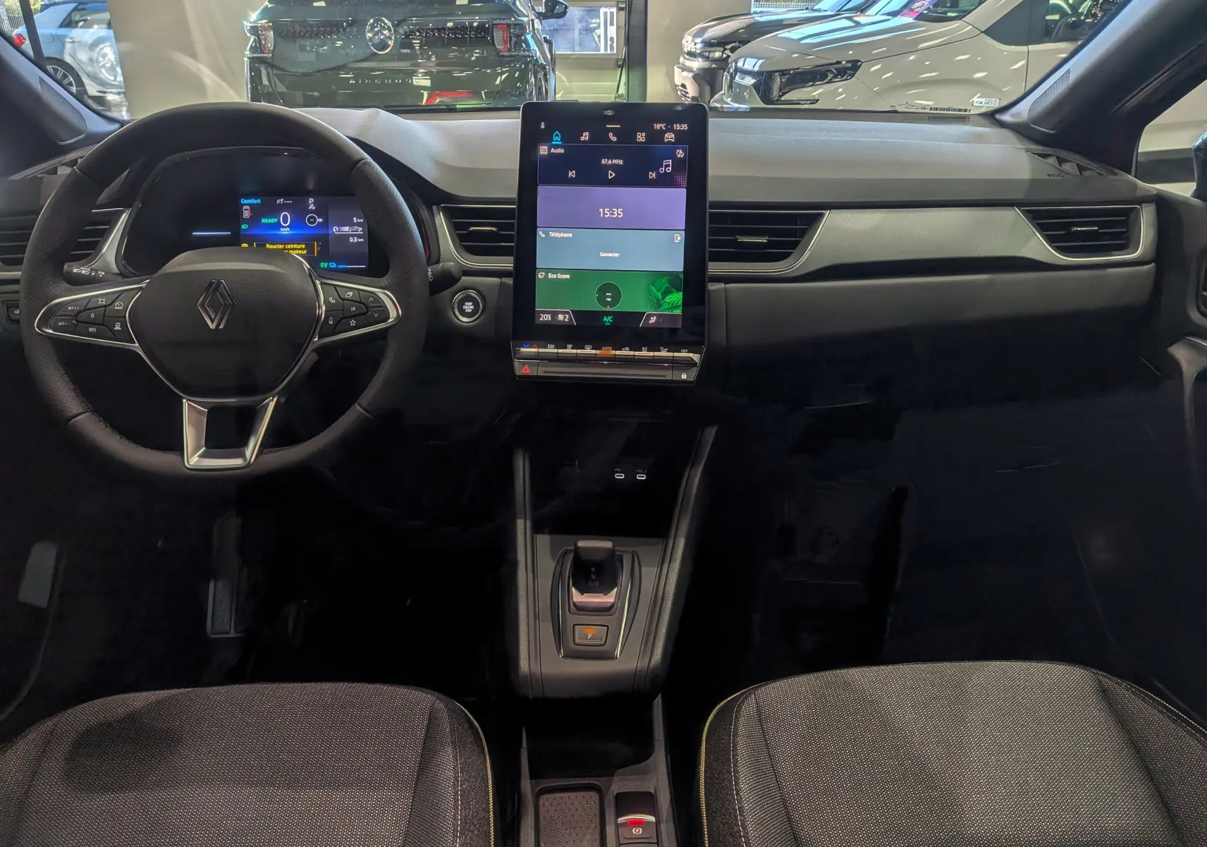 Vue intérieure frontale du tableau de bord du Renault Captur E-TECH 2025 avec écran tactile vertical et volant multifonction.