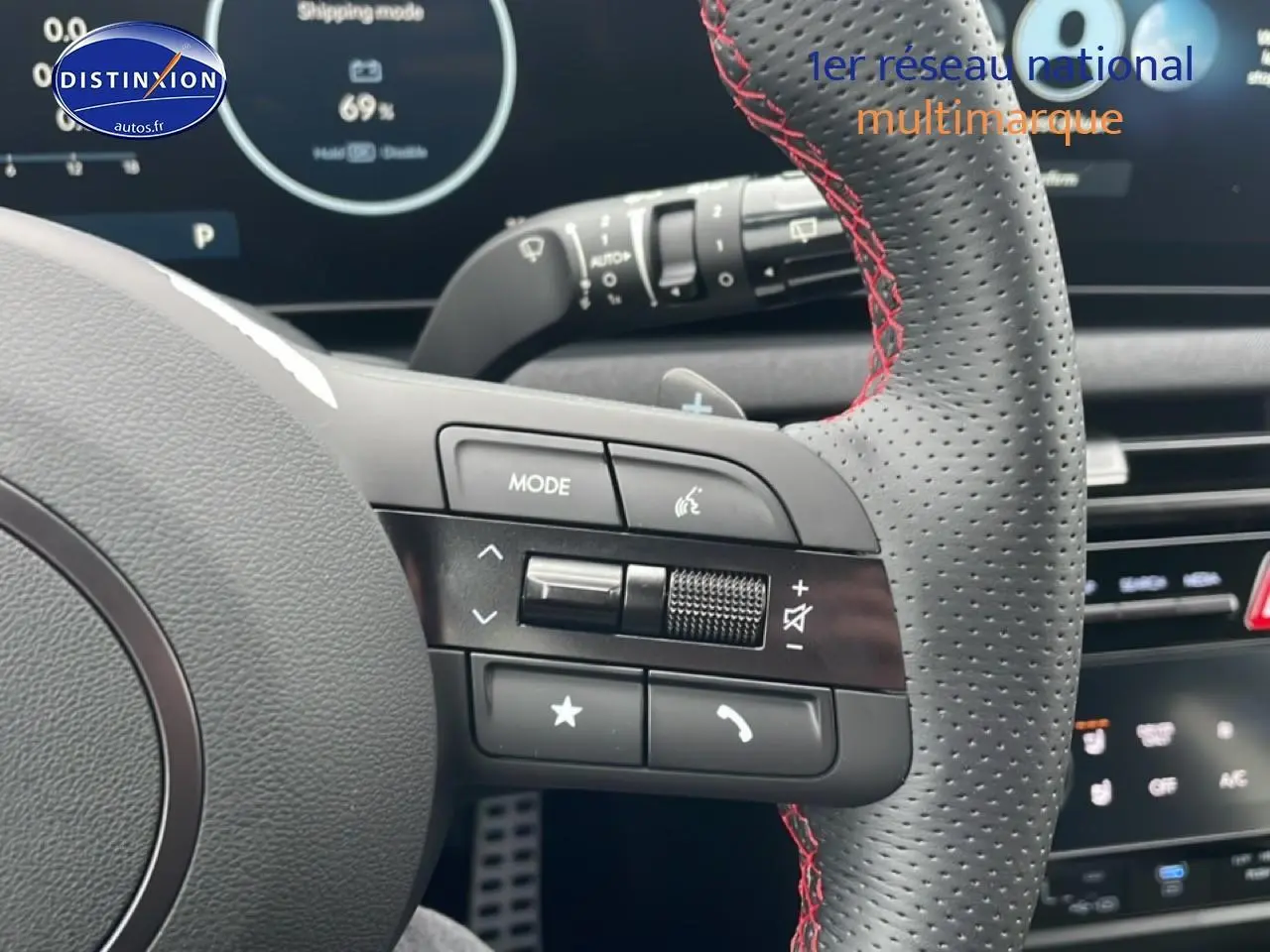 Gros plan sur le volant sport en cuir noir avec surpiqûres rouges du Hyundai Tucson 2025, affichage digital en arrière-plan.