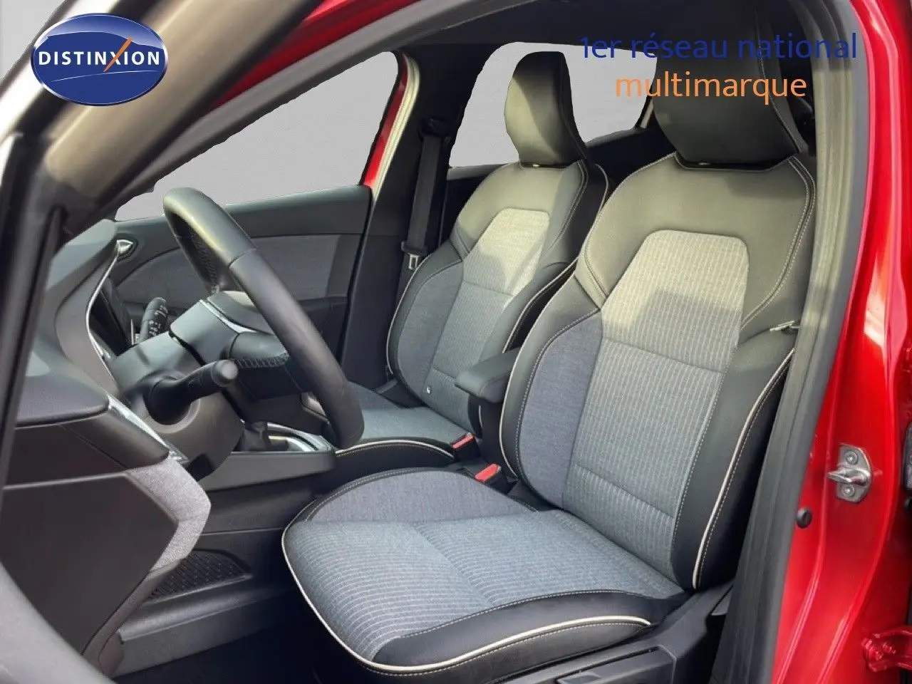 Intérieur de la Renault Clio rouge désir métal, vue côté conducteur ouverte, sièges tissu gris et cuir noir.