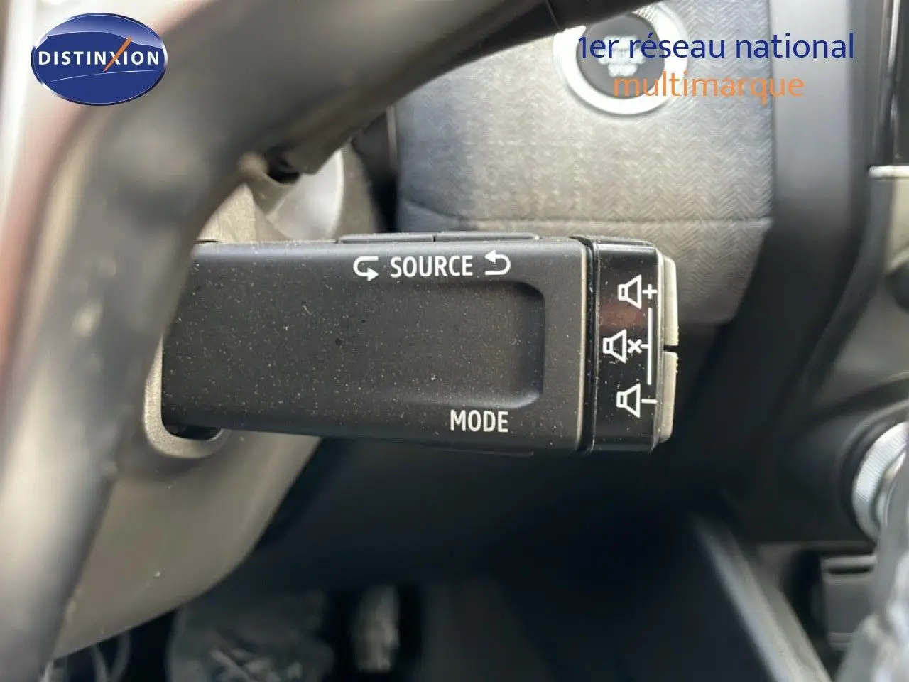 Gros plan sur la commande au volant de la Renault Clio 2025, avec boutons source et mode visibles, intérieur noir.