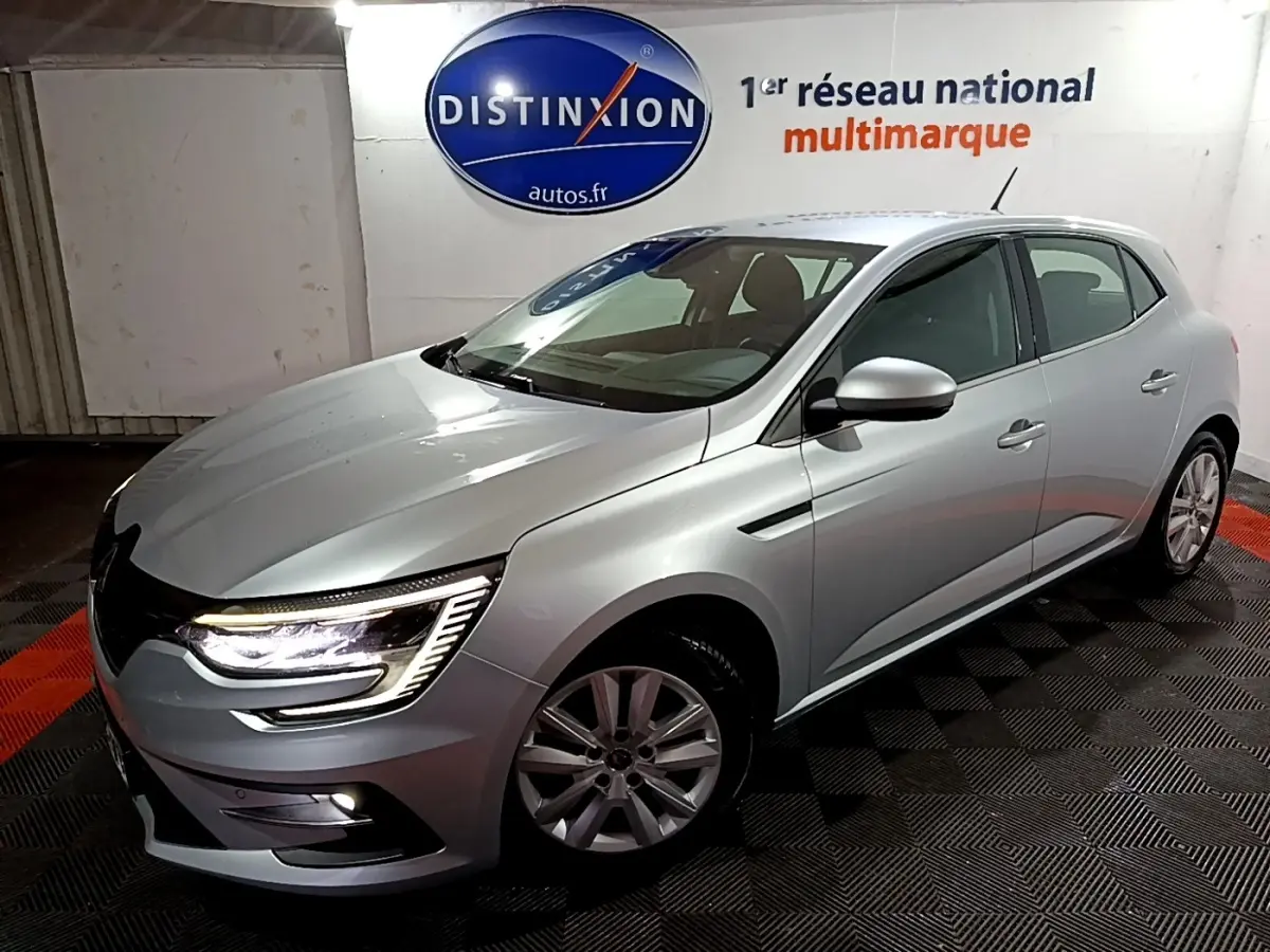 Renault Mégane Business Blue dCi 115 gris clair vue 3/4 avant avec feux LED allumés dans un showroom.