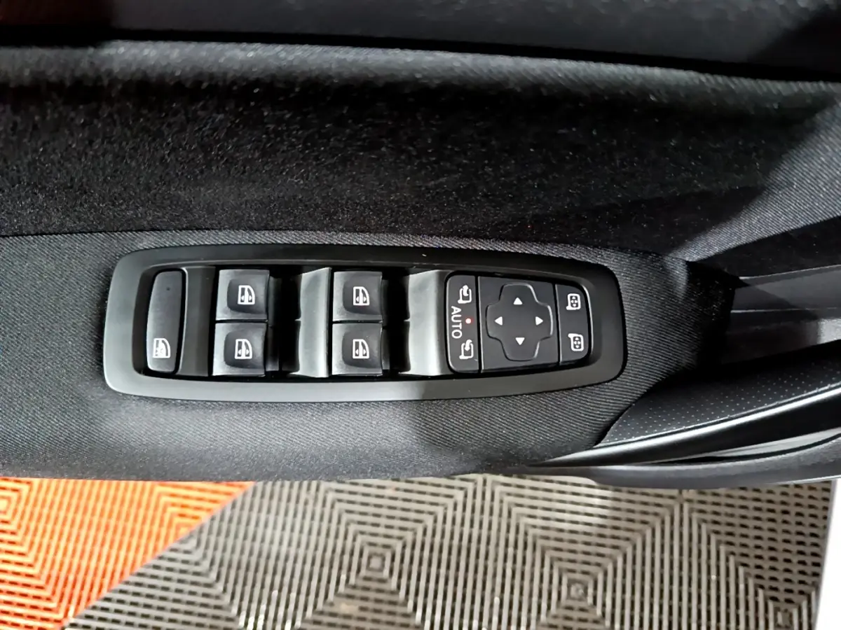 Vue rapprochée des commandes de lève-vitres et réglage des rétroviseurs sur la porte côté gauche d’une Renault Mégane gris clair.