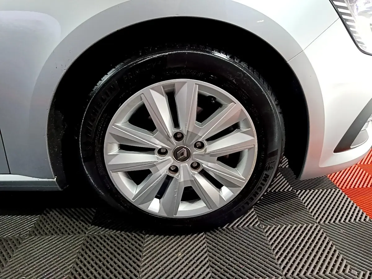 Gros plan sur la roue avant droite gris clair d’une Renault Mégane 2021 avec jante alliage et logo central Renault.