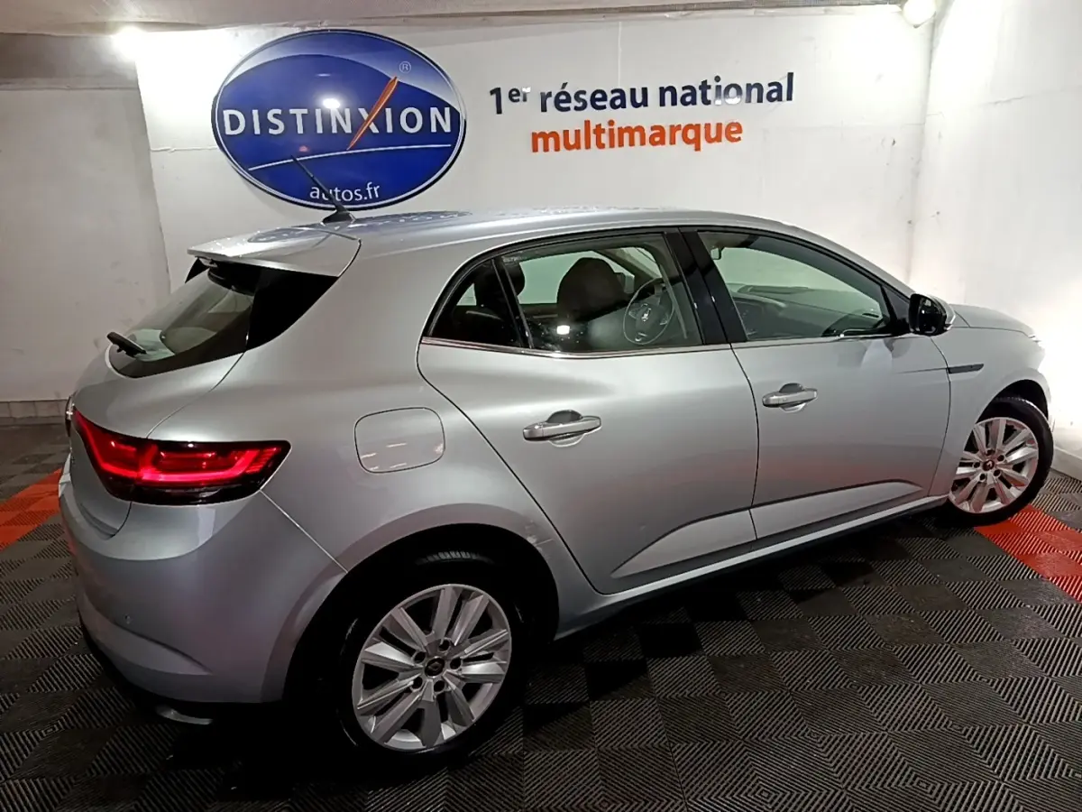 Renault Mégane Business Blue dCi 115 EDC gris clair vue 3/4 arrière droit en intérieur avec feux arrière allumés.