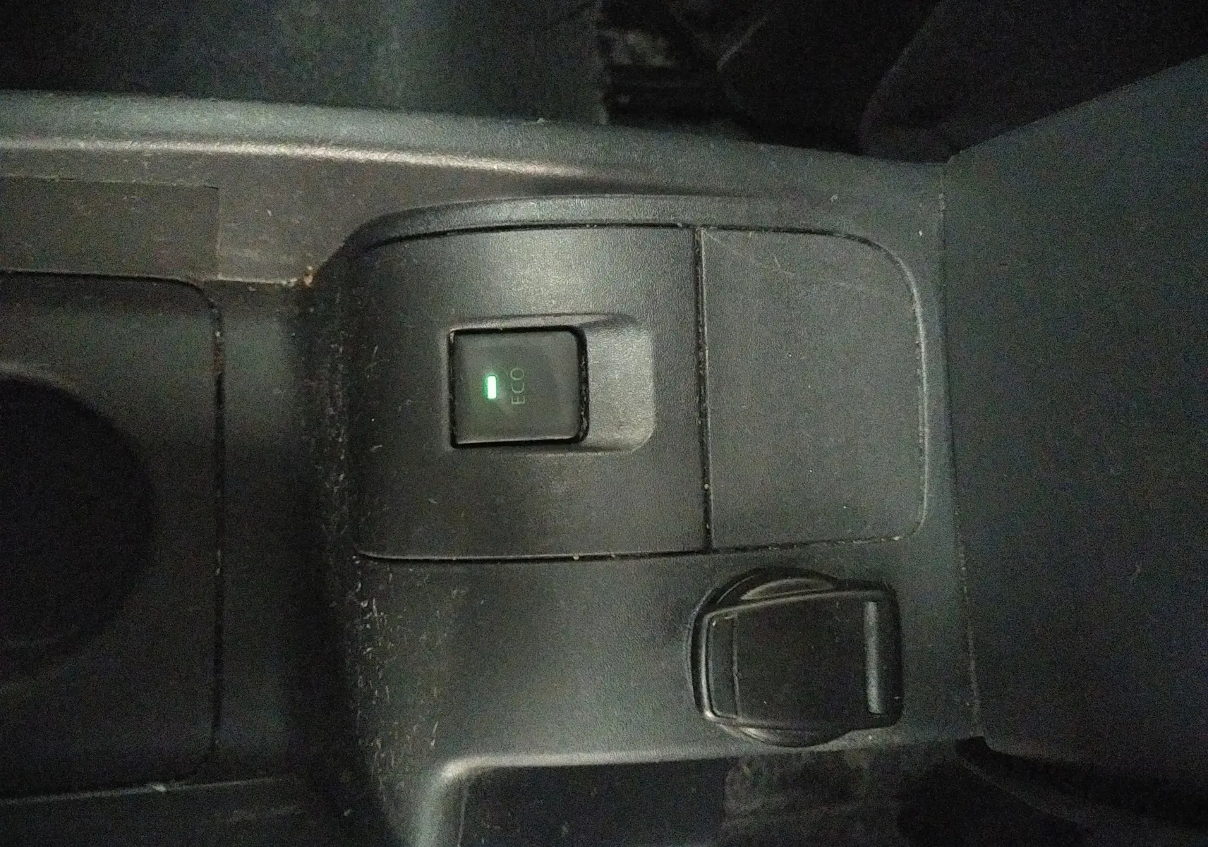 Gros plan sur le bouton ECO activé et prise 12V dans la console centrale noire du Renault Kangoo blanc 2019.