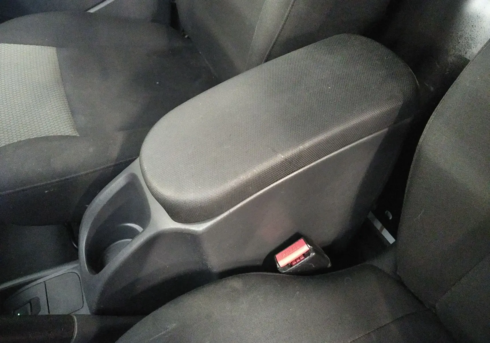 Accoudoir central et sièges avant en tissu noir dans l'habitacle du Renault Kangoo blanc 2019, version Grand Confort.