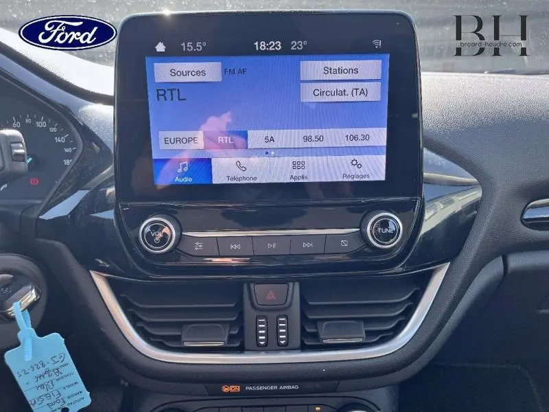 Vue rapprochée de l'écran tactile central et de la console de la Ford Fiesta bleu azur 2022 avec commandes audio et climatisation.