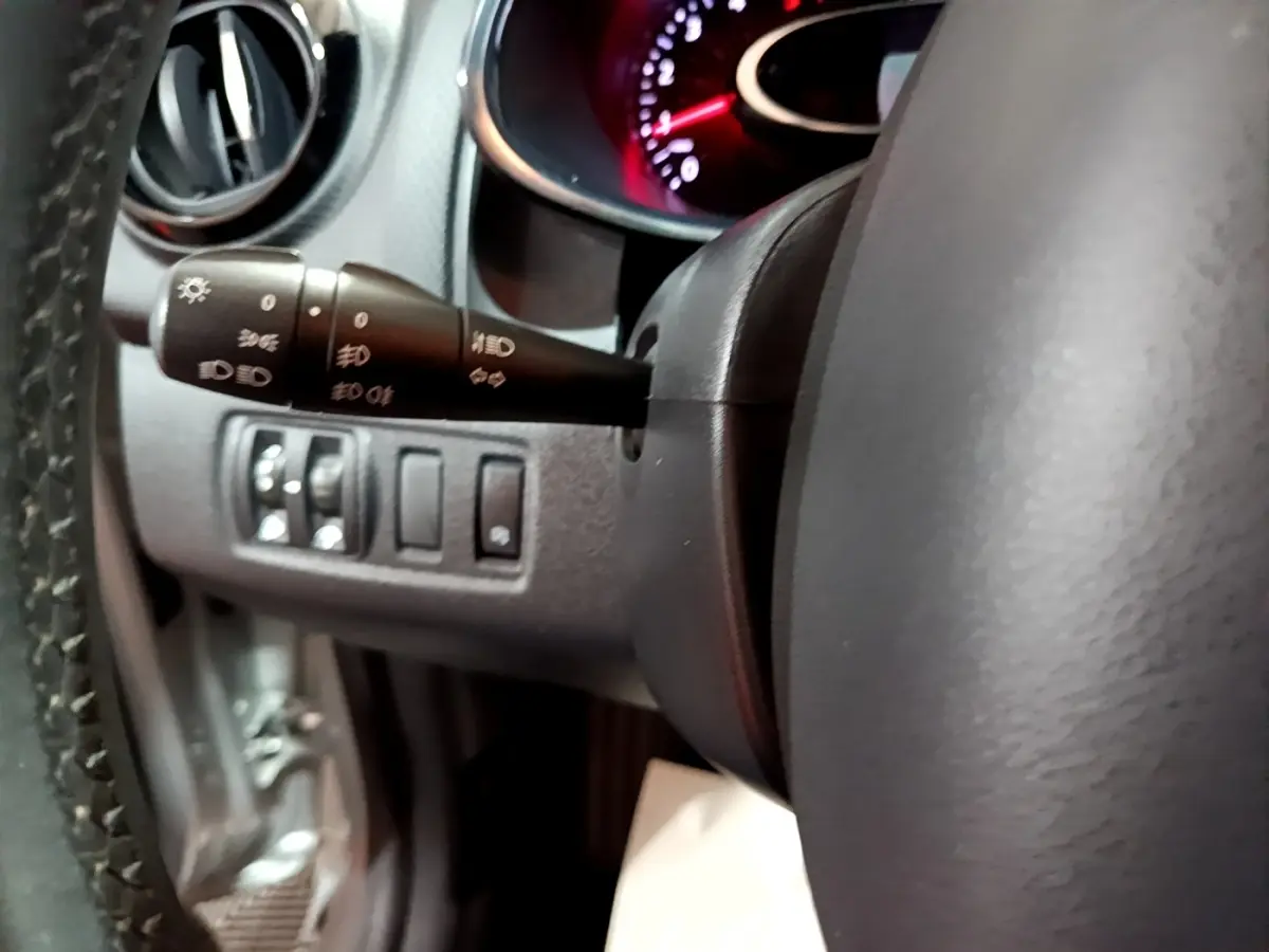 Gros plan sur le volant cuir et la commande des phares à gauche du tableau de bord d’une Renault Clio gris clair 2018.