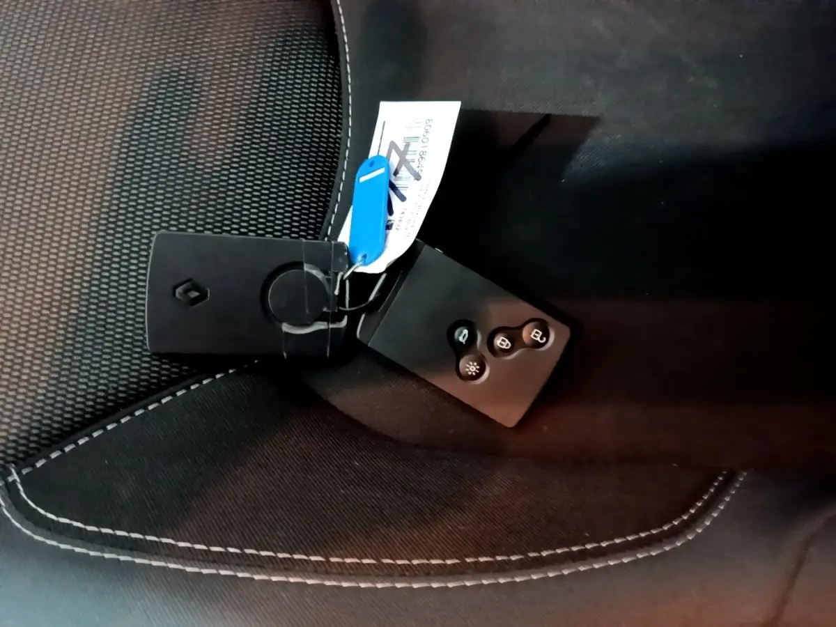Clé Renault posée sur un siège tissu noir avec surpiqûres blanches, vue rapprochée intérieure sans angle véhicule visible.