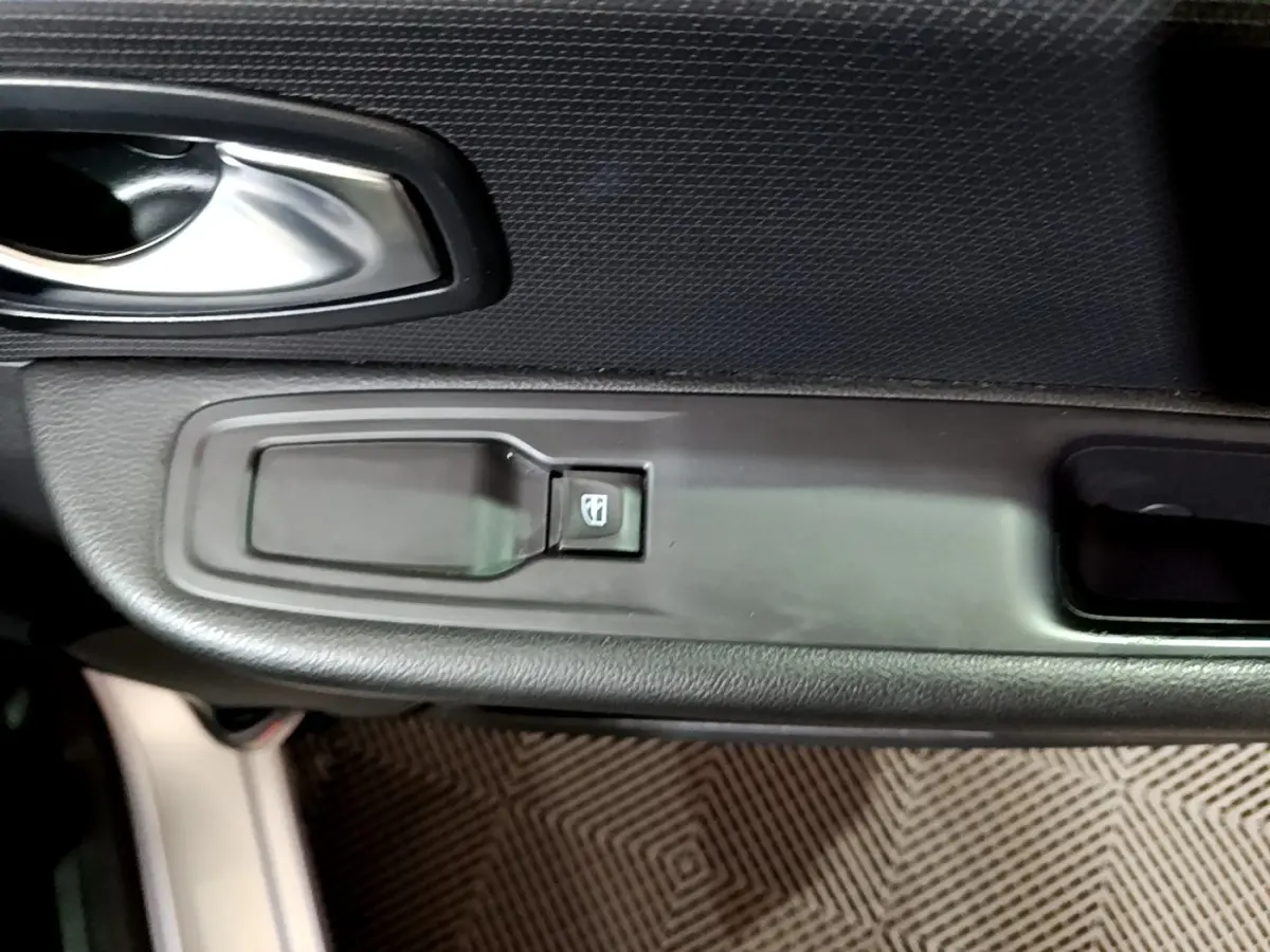 Détail de la commande de lève-vitre côté conducteur sur porte intérieure noire d’une Renault Clio Business gris clair 2018.