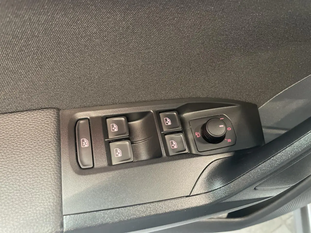 Panneau de commandes des vitres et rétroviseurs côté conducteur dans une SEAT ARONA rouge Passion 2024.