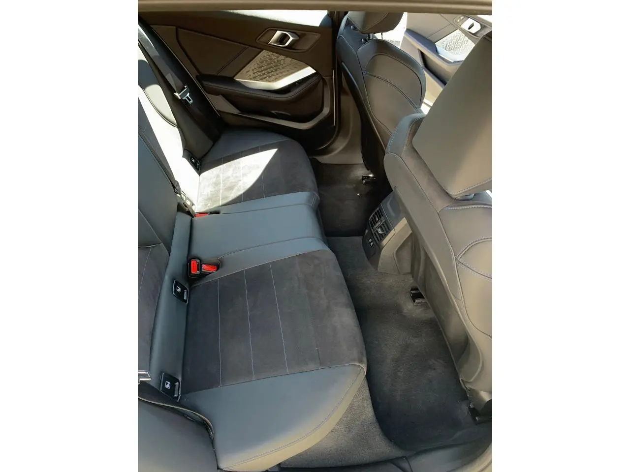 Vue du siège arrière côté gauche de la BMW Série 1 118d M Sport 2025 avec sellerie Alcantara noire et surpiqûres bleues.