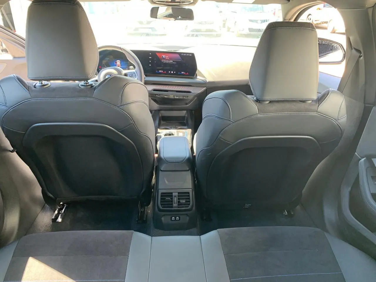 Vue arrière de l'intérieur noir Alcantara de la BMW Série 1 118d M Sport avec console centrale et écran digital.