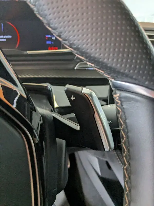 Gros plan sur la palette de changement de vitesse + du volant en cuir perforé dans la Peugeot 508 SW gris selenium 2024.