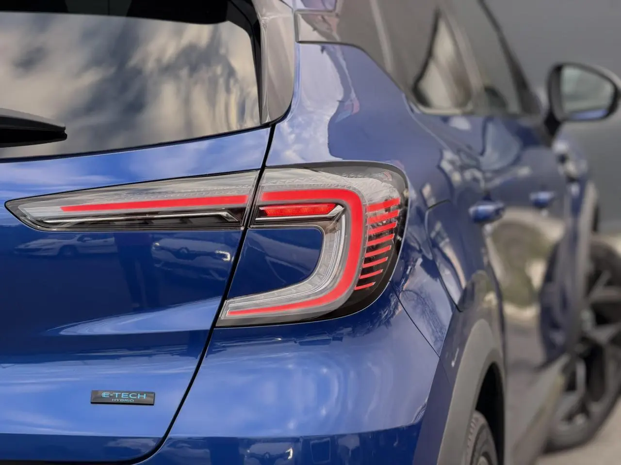 Vue arrière côté gauche du Renault Captur 2025 Bleu Iron avec feux LED distinctifs et badge E-Tech Hybrid.