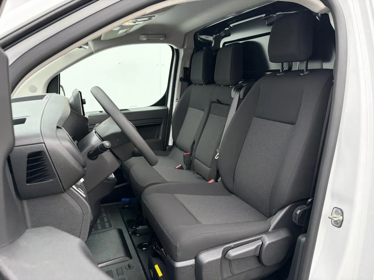 Vue intérieure côté conducteur du Peugeot Expert Fourgon blanc Icy, montrant la banquette 3 places en tissu bi-ton noir et gris.