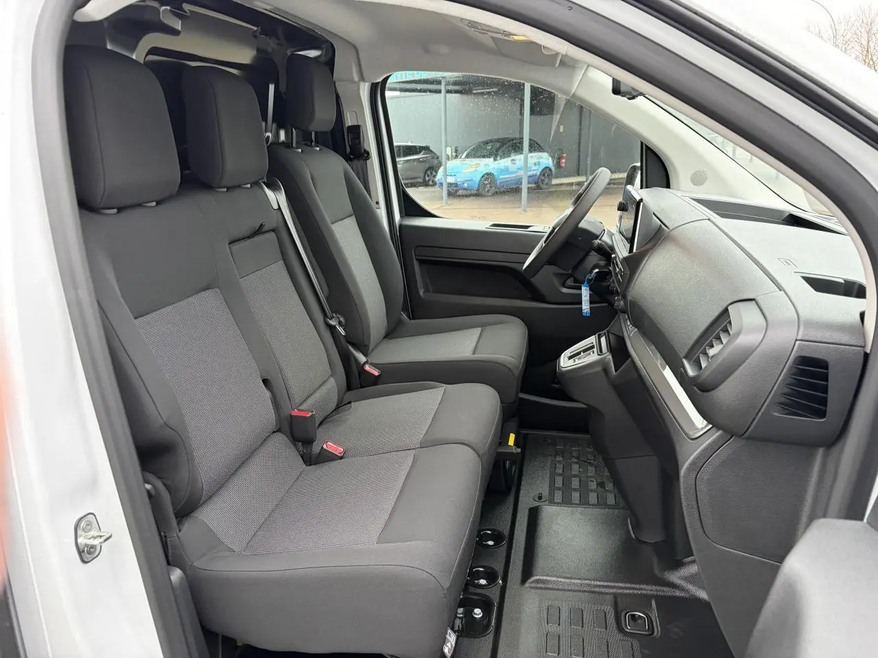 Vue intérieure côté conducteur du Peugeot Expert Fourgon blanc Icy, montrant la banquette 3 places et le tableau de bord.