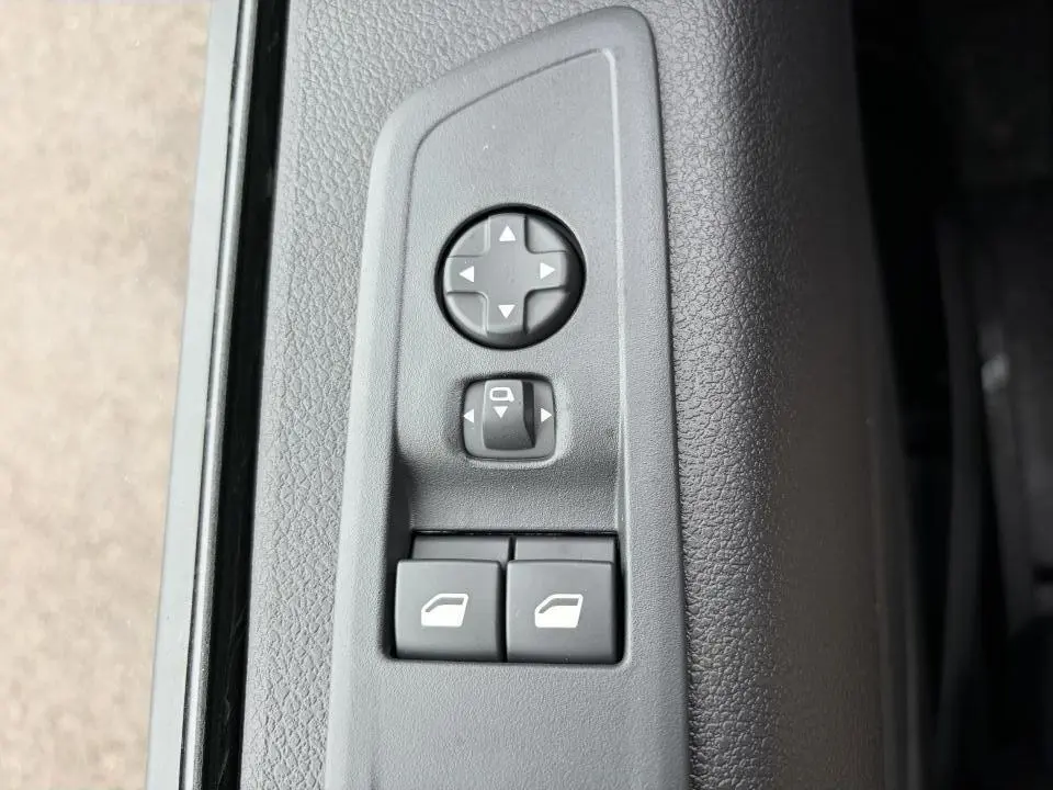 Gros plan sur les commandes de réglage des rétroviseurs et des vitres sur la porte intérieure grise du Peugeot Expert Fourgon blanc.