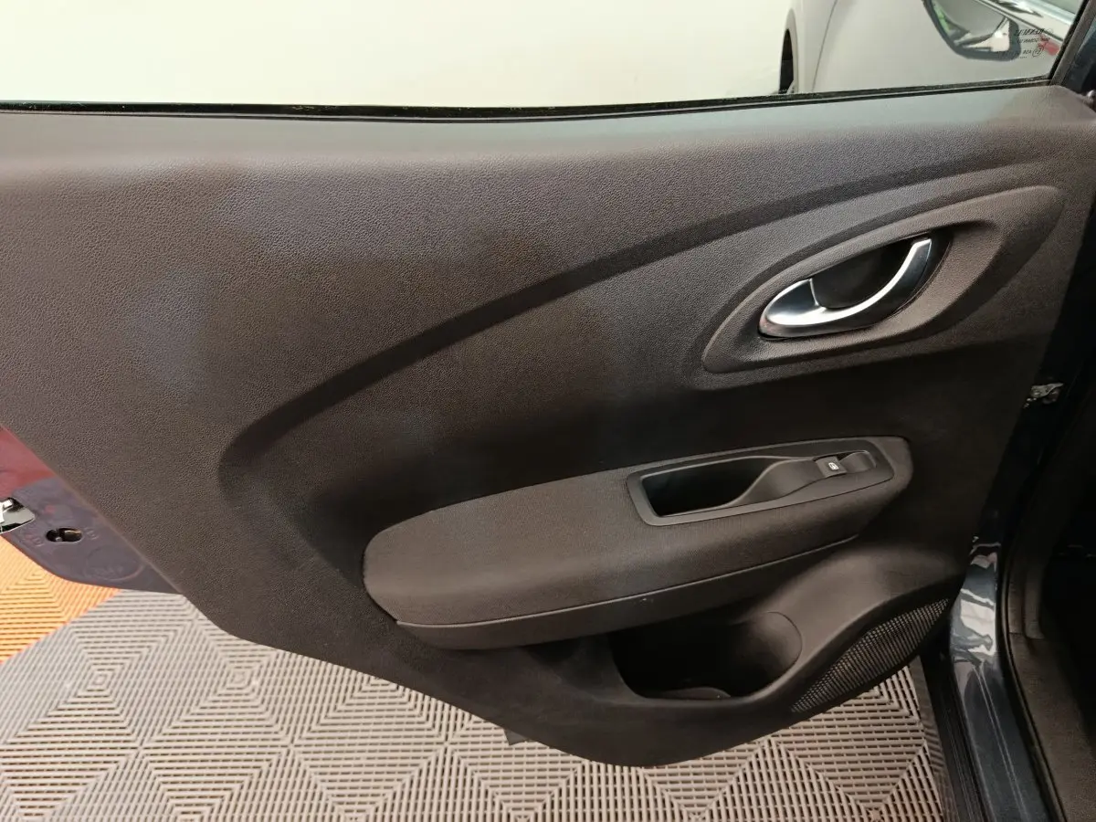 Gros plan sur la porte intérieure côté droit du Renault Kadjar gris foncé, montrant la poignée et les commandes de fenêtre.