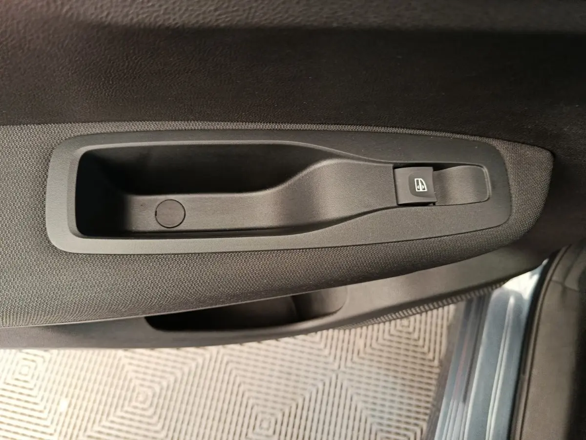 Poignée intérieure de porte côté droit du Renault Kadjar gris foncé 2022 avec bouton de commande de vitre électrique.