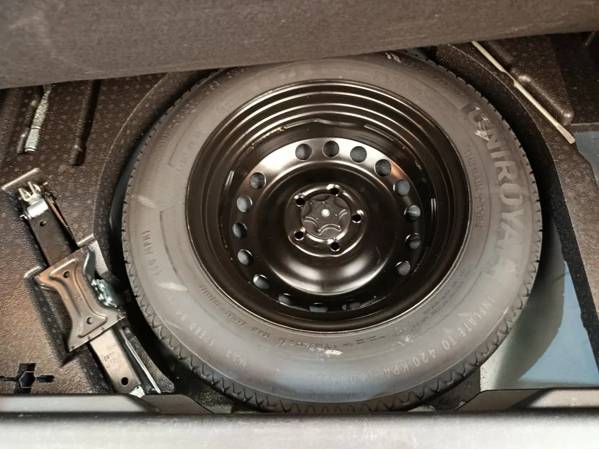 Vue rapprochée de la roue de secours noire et du cric dans le coffre d’un Renault Kadjar gris foncé 2022.