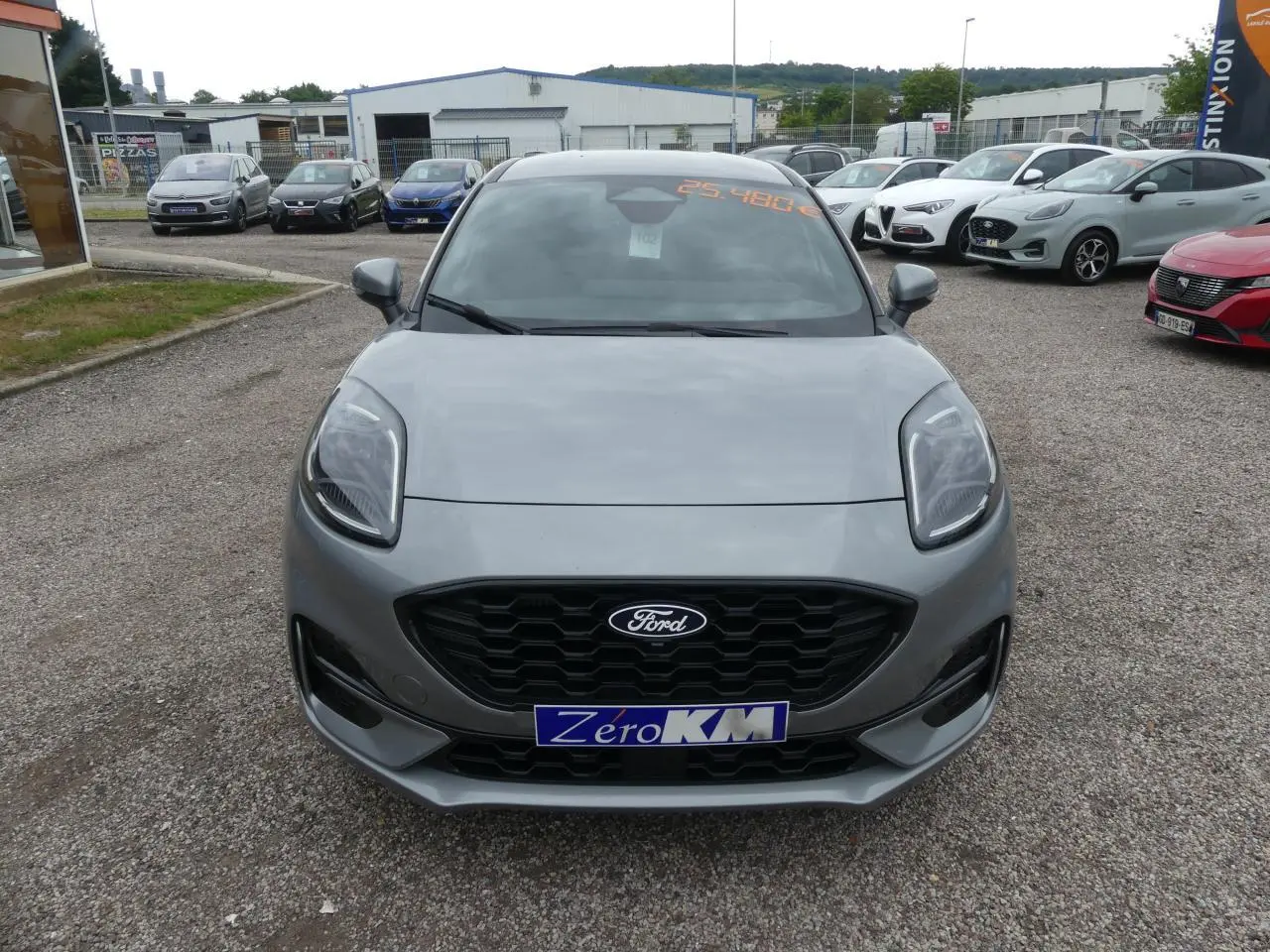 Vue avant d'une Ford Puma 2025 gris métallisé avec calandre noire et phares LED, en extérieur sur parking.