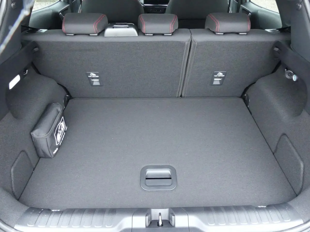 Vue du coffre spacieux et propre du Ford Puma 2025 gris métallisé, avec sièges arrière rabattus et kit de secours visible.