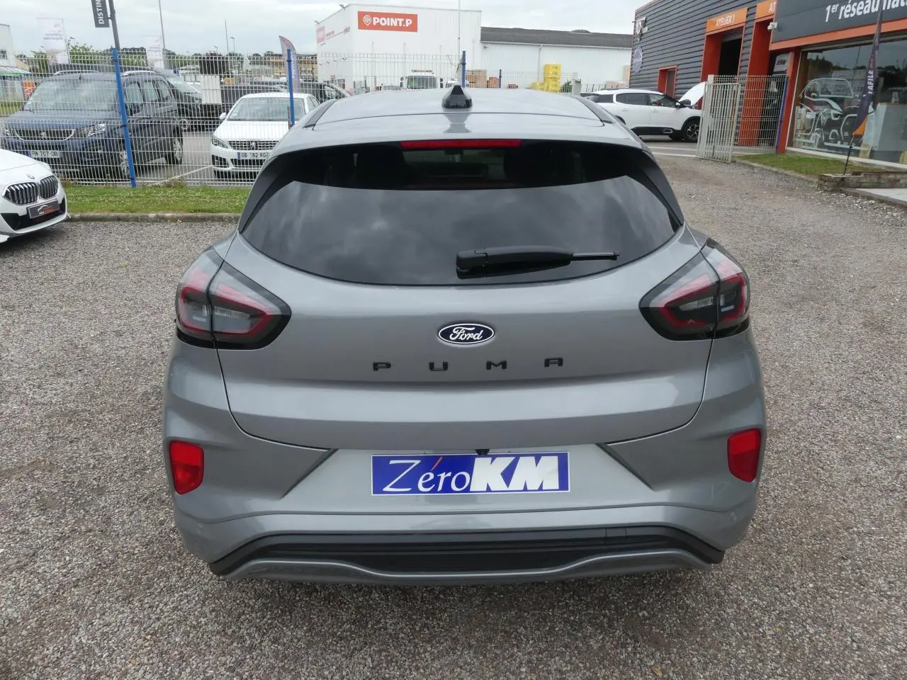 Vue arrière d'un Ford Puma gris métallisé 2025 avec vitres arrière surteintées et logo Ford bien visible.
