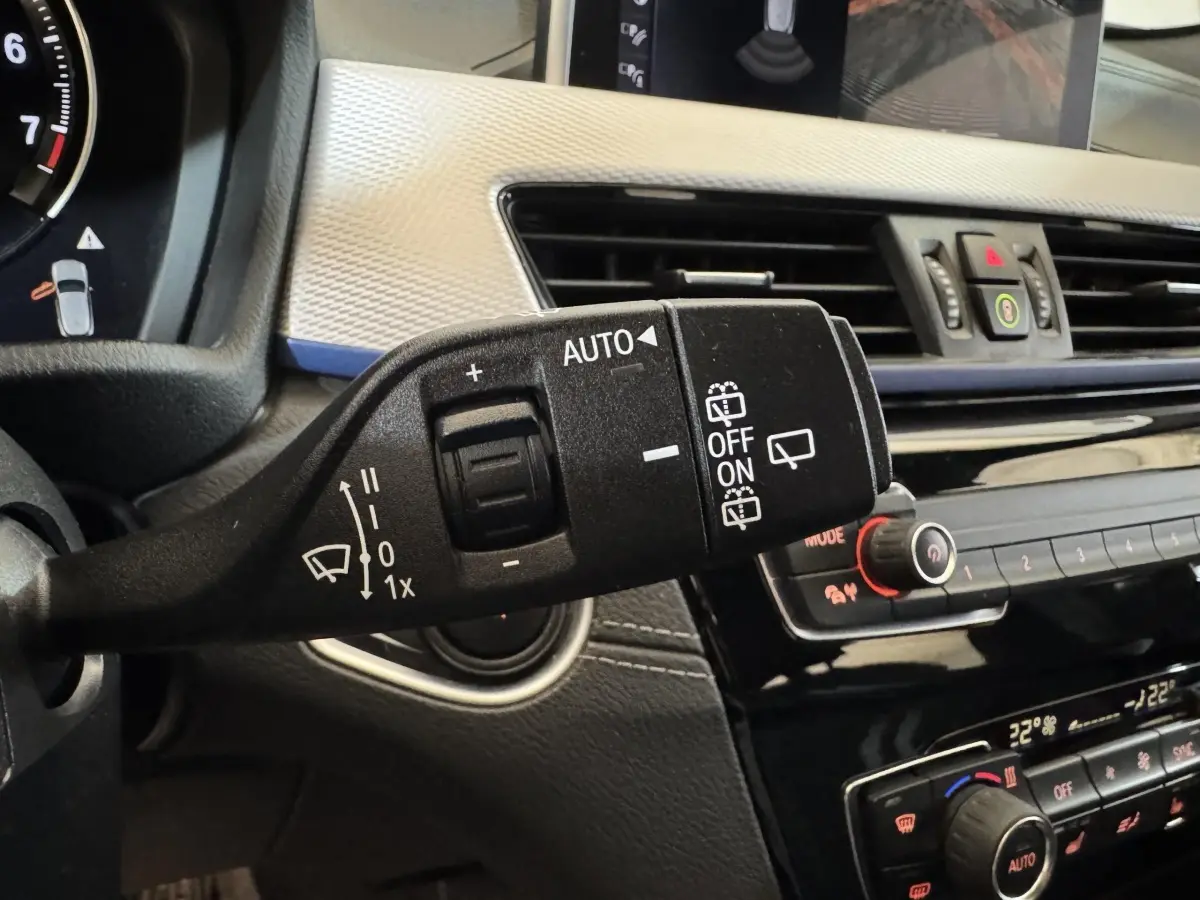 Gros plan sur la commande d’essuie-glace et tableau de bord noir et argenté d’une BMW X2 xDrive25e bleu 2021.