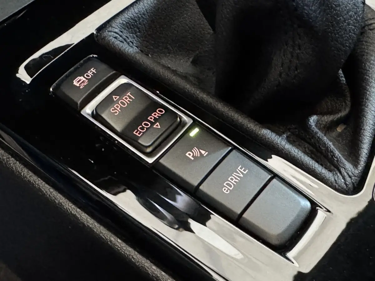Gros plan sur les boutons de mode de conduite et assistance au stationnement du BMW X2 xDrive25e bleu 2021.
