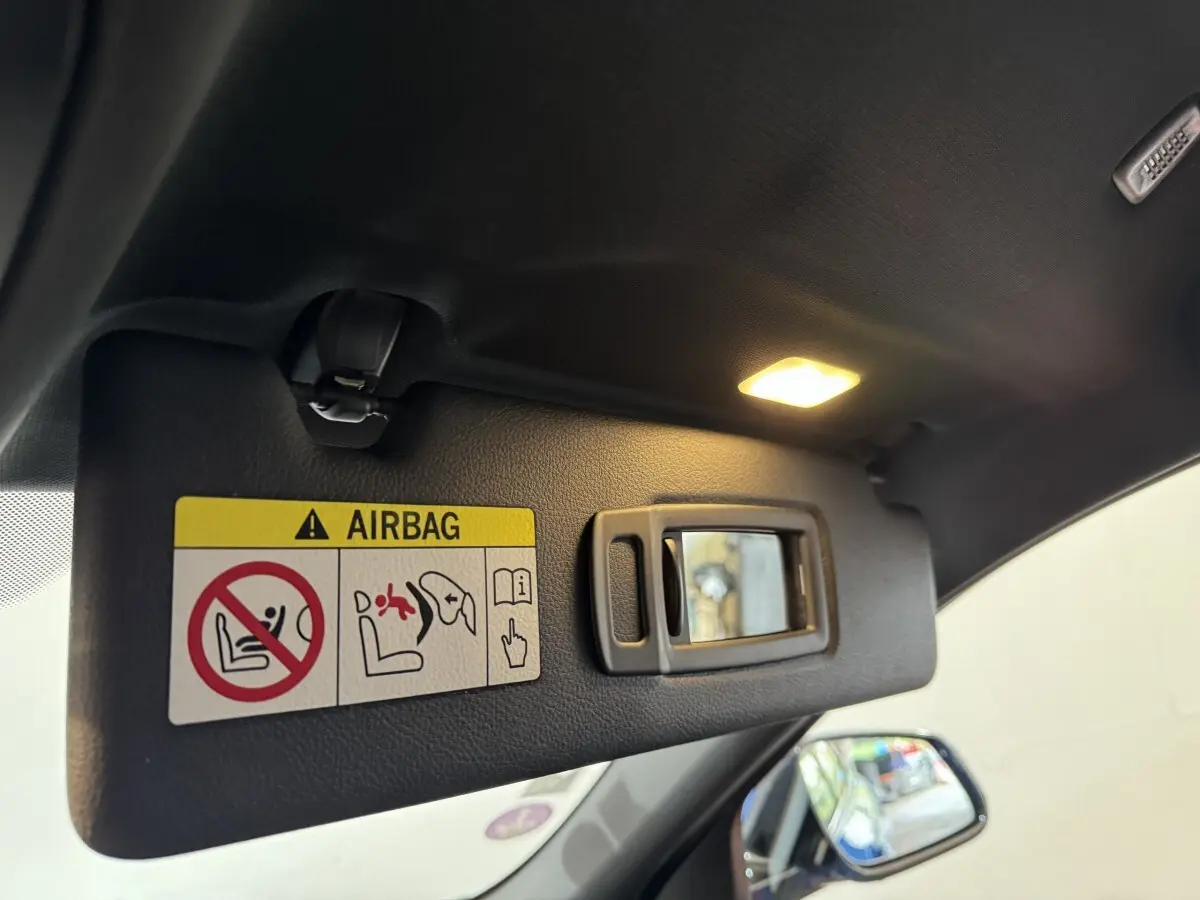 Détail du pare-soleil côté conducteur avec miroir et avertissement airbag dans un BMW X2 bleu 2021.