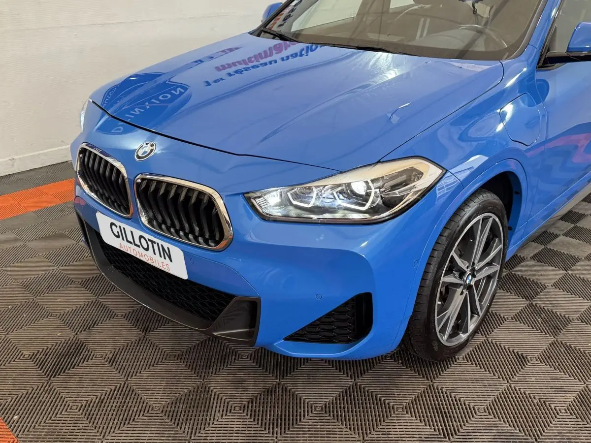 Vue 3/4 avant droite d’une BMW X2 xDrive25e M Sport bleu avec calandre double haricot et phares LED distinctifs.
