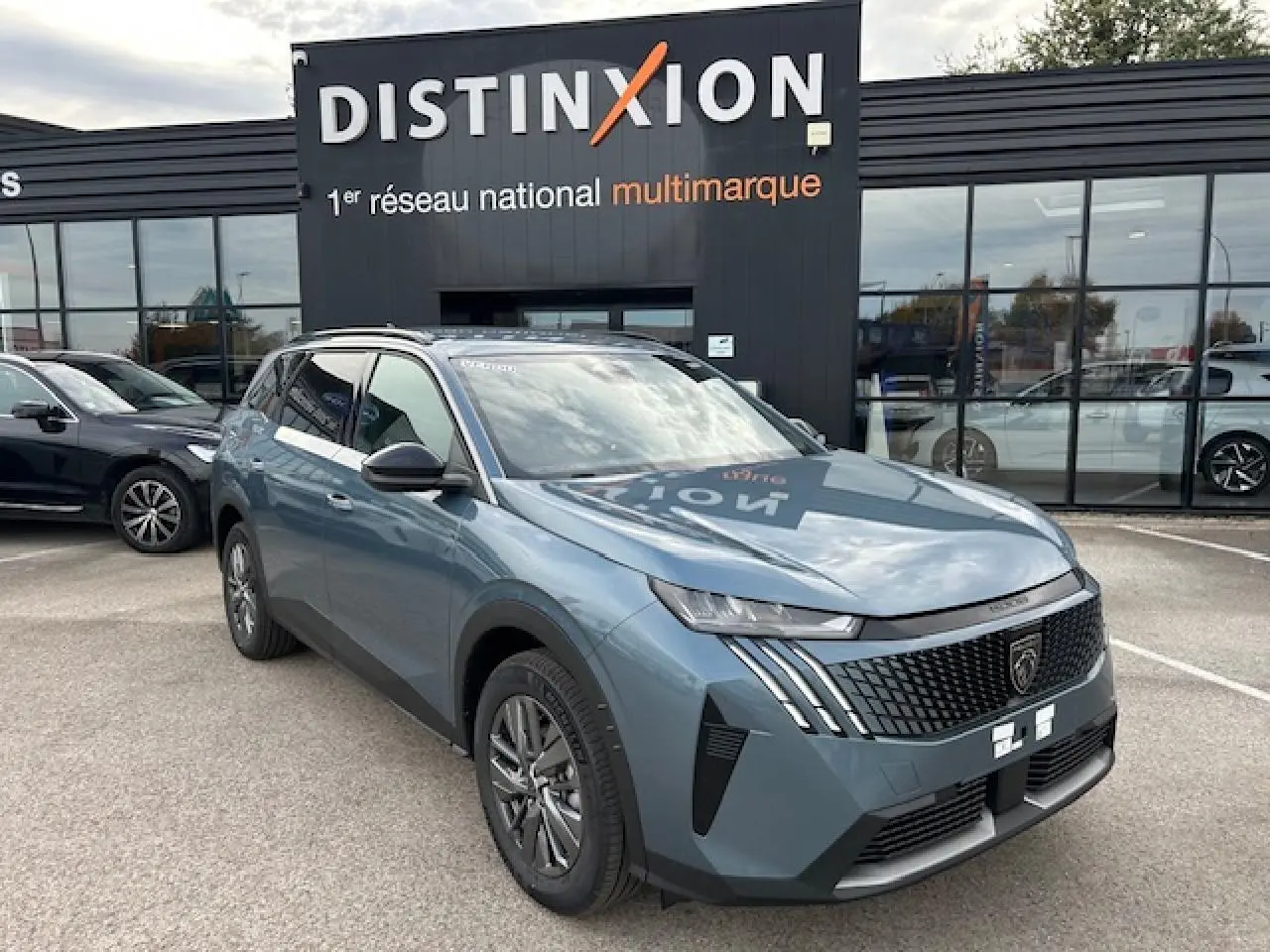 Peugeot 5008 bleu Ingaro métal vue 3/4 avant avec calandre distinctive et feux LED 3 griffes, devant concession Distinxion.