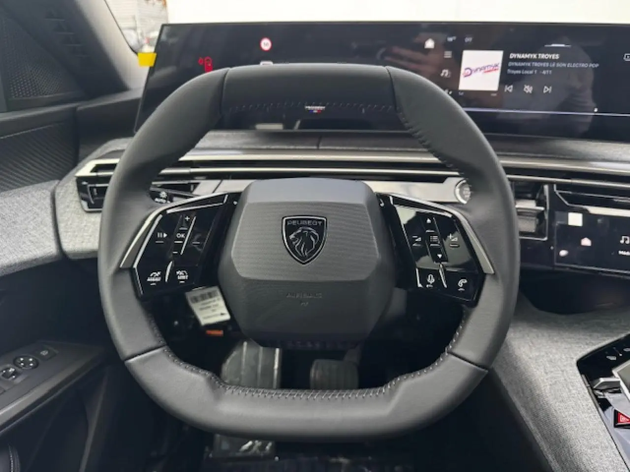 Volant compact cuir noir avec logo Peugeot, tableau de bord numérique panoramique et finition tissu gris dans un Peugeot 5008 2025.