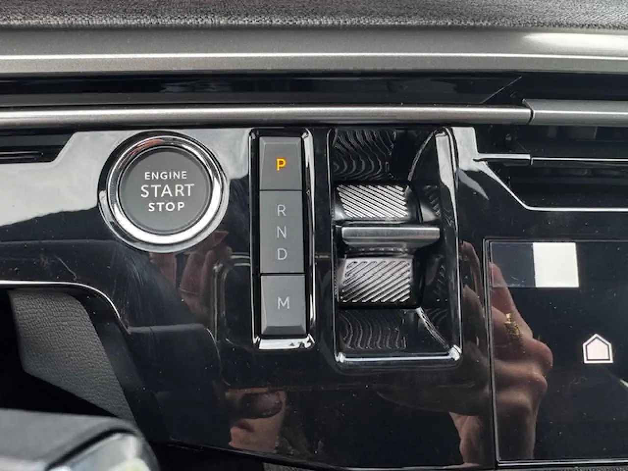 Gros plan sur la console centrale noire brillante du Peugeot 5008 Bleu Ingaro, avec bouton start/stop et commandes de boîte auto.