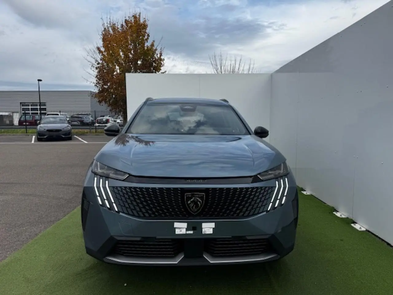 Vue frontale du Peugeot 5008 bleu Ingaro métallisé avec calandre noire et feux LED à griffes distinctifs.