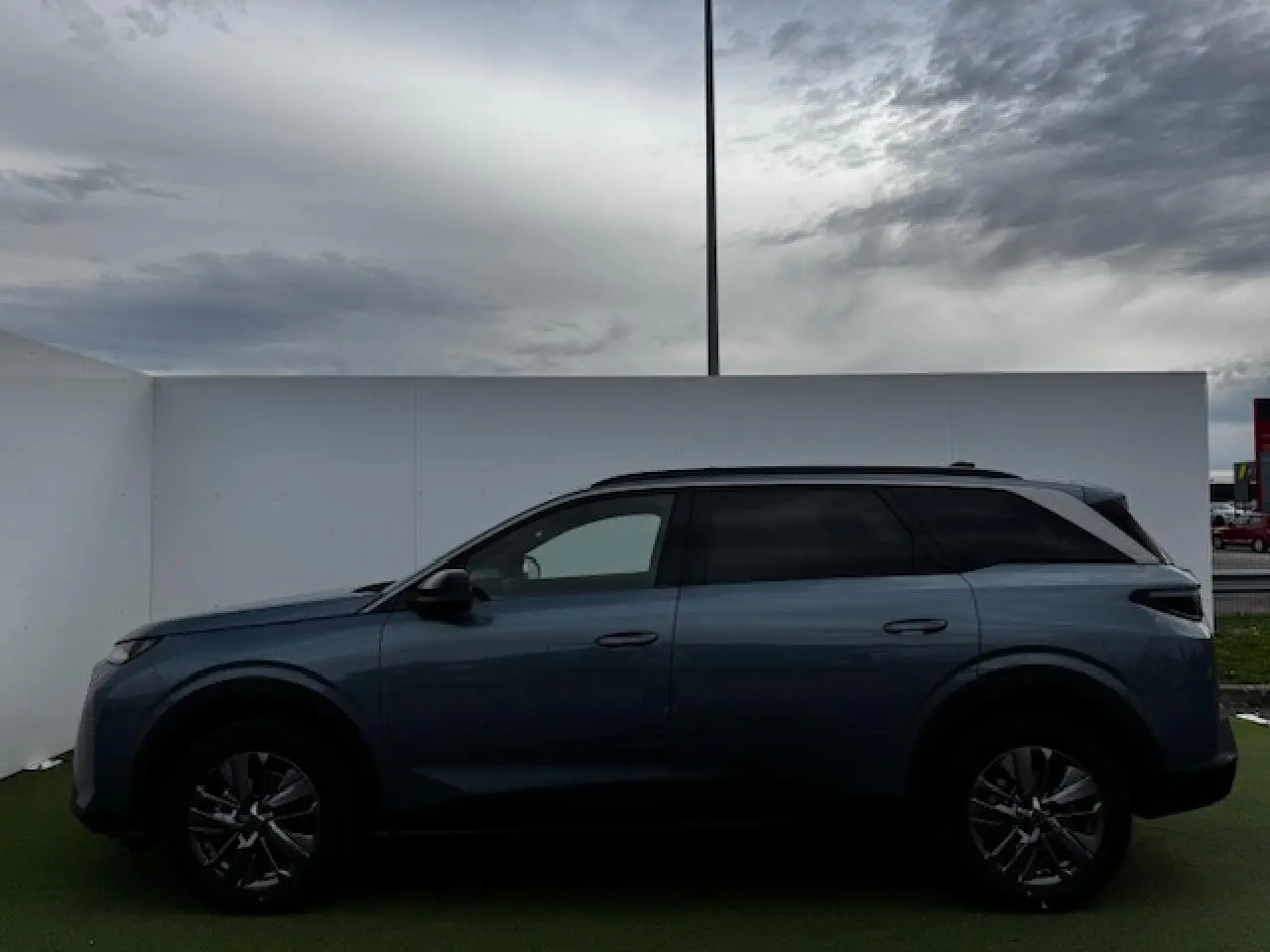 Profil latéral droit du Peugeot 5008 bleu Ingaro métallisé avec jantes alliage et toit noir contrasté.