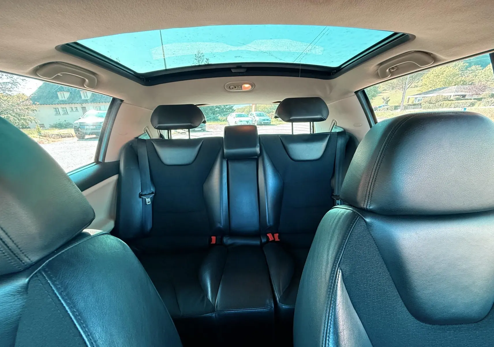 Vue intérieure arrière du Renault Avantime gris, montrant les sièges en cuir noir et le toit panoramique vitré.